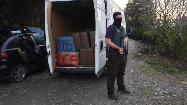 Un agente de la Guardia Civil ante una furgoneta cargada de fardos de hachís