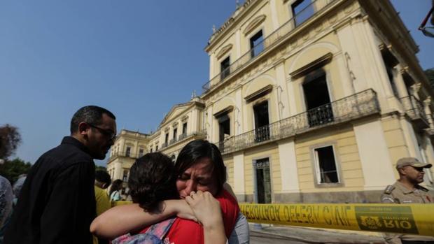 Dos funcionarias lloran ante la fachada del Museo Nacional de Río de Janeiro
