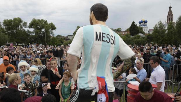 Varios aficionados, frente a una estatua de Messi