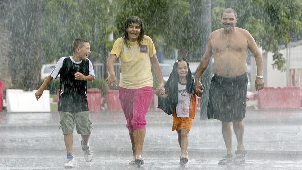 Imagen de una familia paseando bajo la tormenta cerca de la playa de La Malvarrosa de Valencia.
