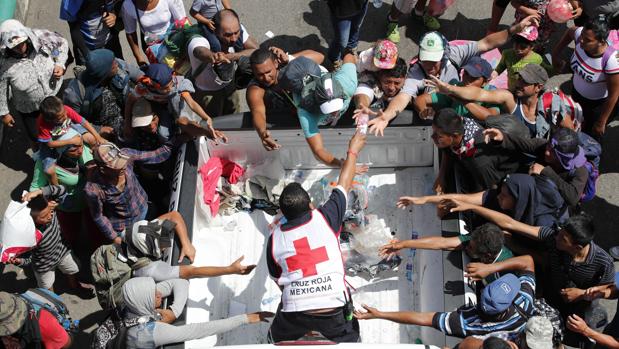 Personal de la cruz roja entrega agua a migrantes hondureños que continúan recorriendo otro tramo del territorio mexicano