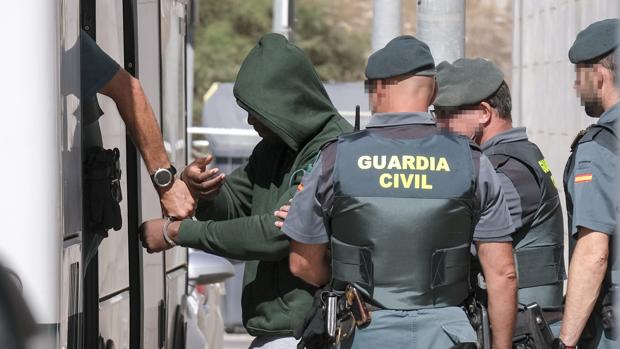 Agentes de la Guardia Civil trasladan a uno de los detenidos en los juzgados.