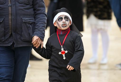 Un padre lleva de la mano a su hijo disfrazado para Halloween